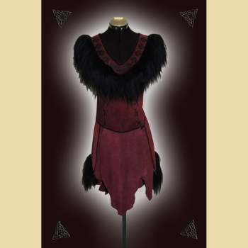 Dress made of burgundy suede. Decorated with lavish sheepskin trim, black trimmings, and black ornaments at the neckline and side panels. The skirt section shows the natural edges of the goat suede.