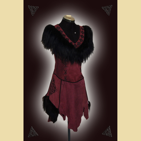 Dress made of burgundy suede. Decorated with lavish sheepskin trim, black trimmings, and black ornaments at the neckline and side panels. The skirt section shows the natural edges of the goat suede.