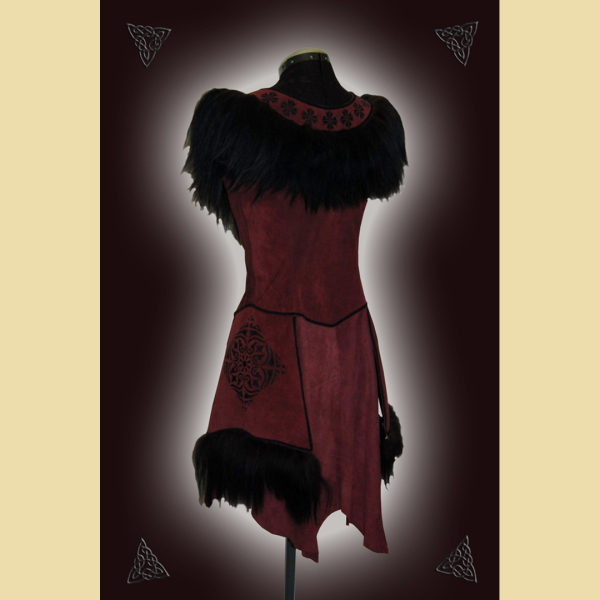 Dress made of burgundy suede. Decorated with lavish sheepskin trim, black trimmings, and black ornaments at the neckline and side panels. The skirt section shows the natural edges of the goat suede.