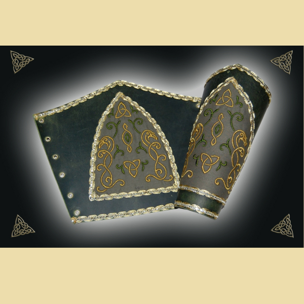 Armstulpen aus olivgrünem Fettleder. Sie sind mit einer aus dem Angelsächsichen inspirierten Stickerei und goldener Borte verziert. Sie werden mit Lederbändern geschnürt.