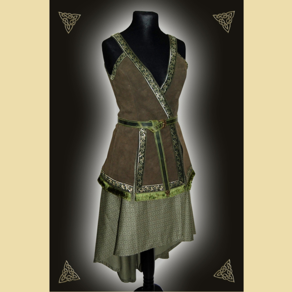 Kleid aus olivgrünem Rindveloursleder und einem zart gemusterten Baumwollstoff. Das Kleid ist verziert mit einem geknotet getragenem Gürtel, dekorativen Webborten und Fransenbesatz.