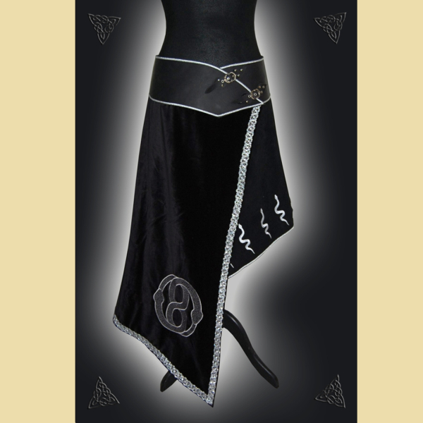 A hip-hugging, asymmetrical skirt made of black oiled leather, cowhide suede, and cotton velvet. It is embellished with silver braiding and trim, as well as decorative snake embroidery.